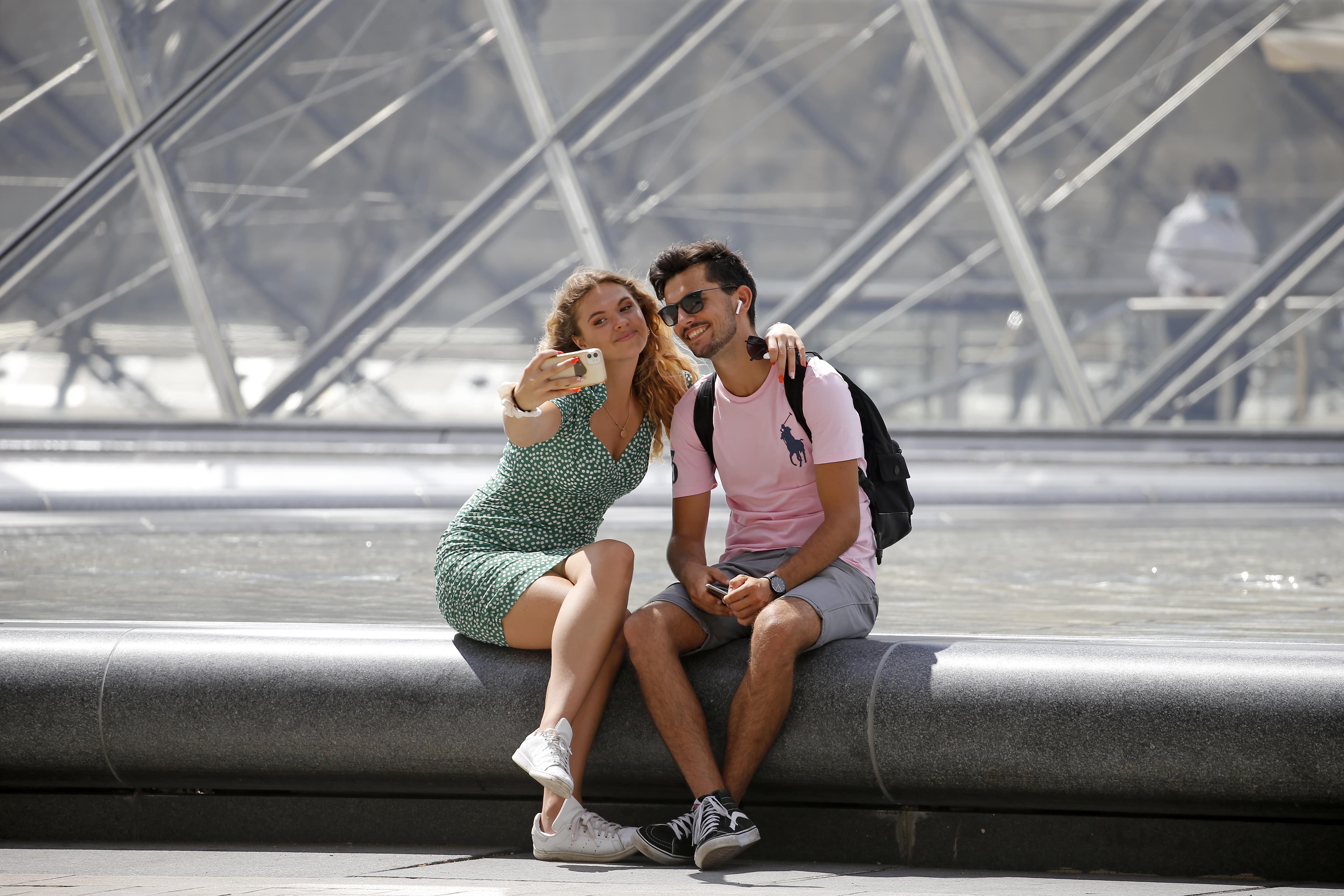 Turistas tiram foto em frente à pirâmide do Louvre