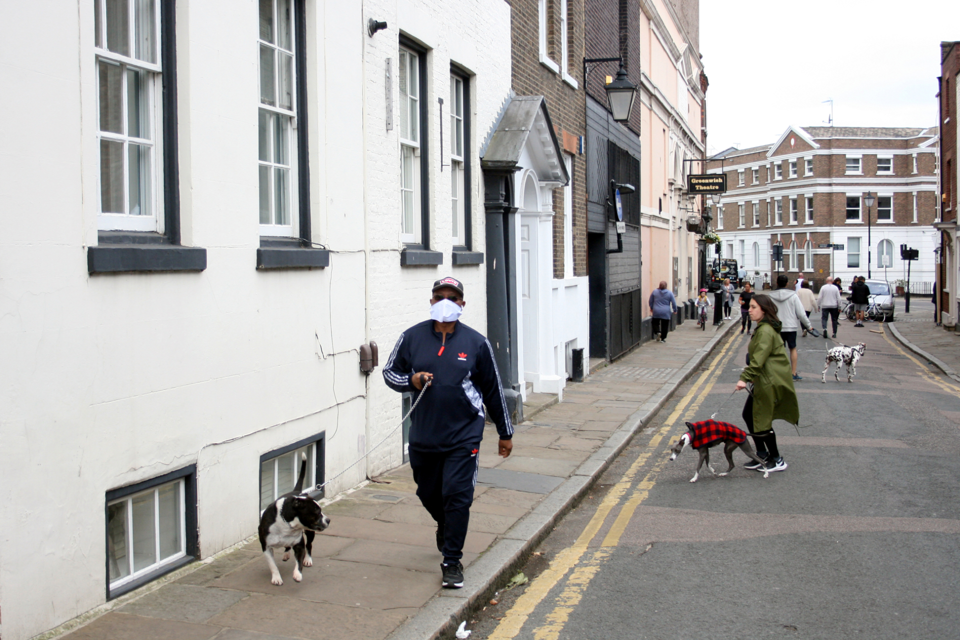 Homem com máscara caminha com seu cachorro em Greenwich, Londres