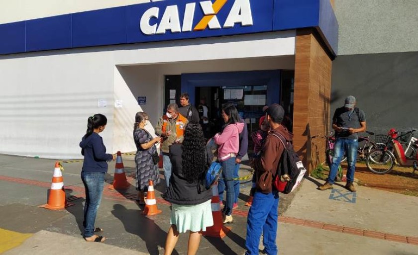 Funcionário da Caixa Econômica auxilia pessoas interessadas na retirada do auxílio emergencial