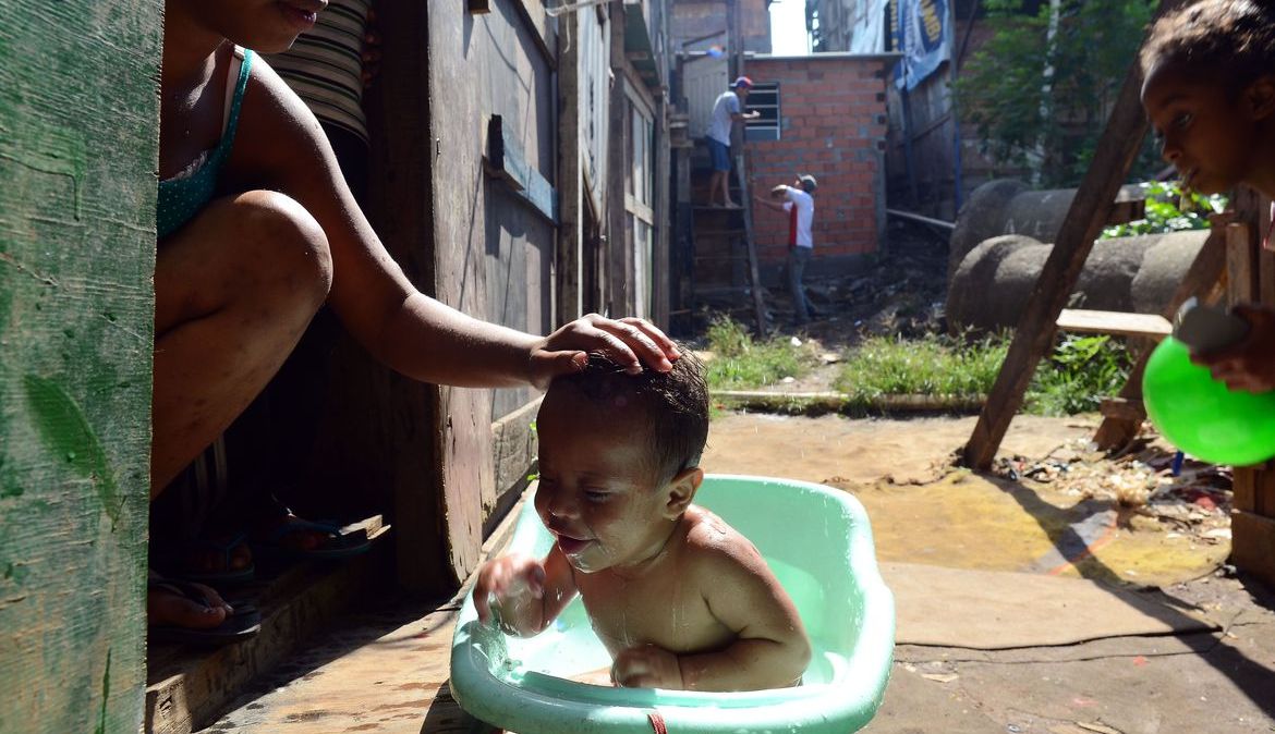 Bebê toma banho em favela