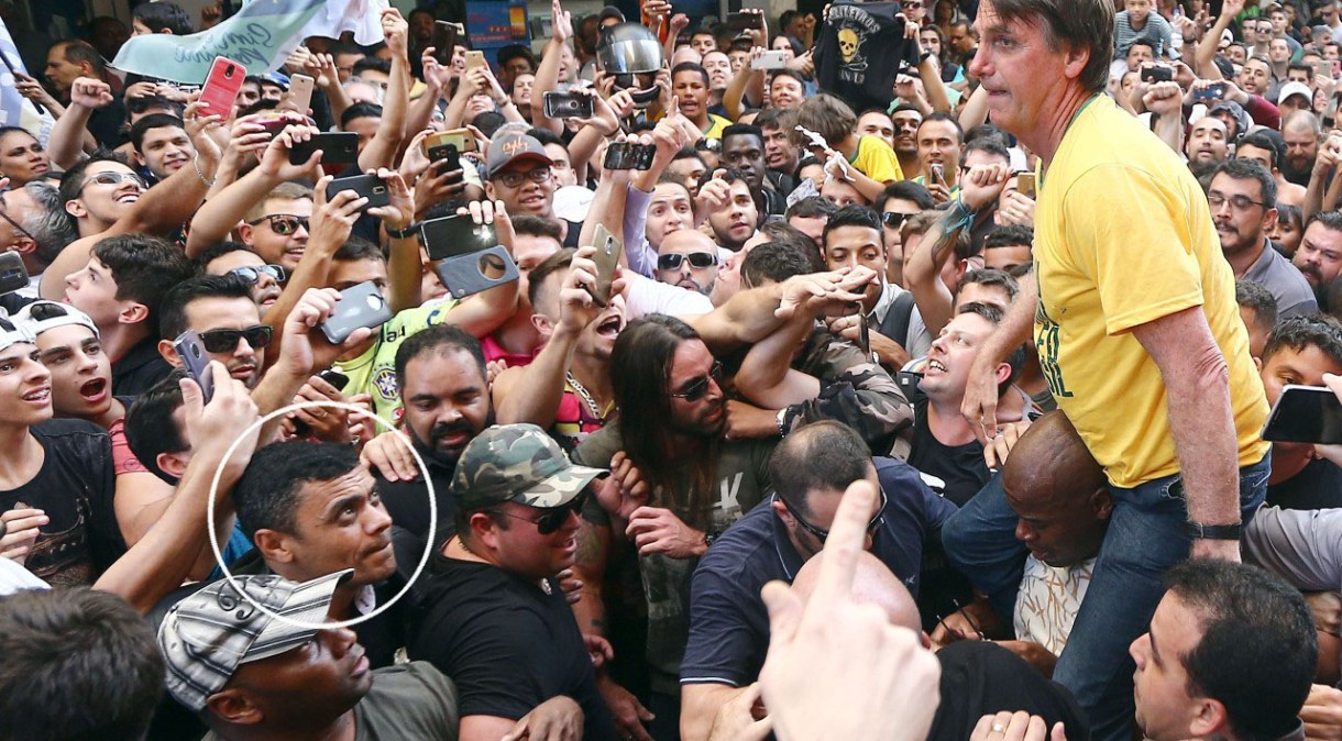 O então candidato à Presidência, Jair Bolsonaro, é carregado nas costas por militantes durante ato político em Juiz de Fora, em Minas Gerais. No detalhe no circulo, Adélio Bispo