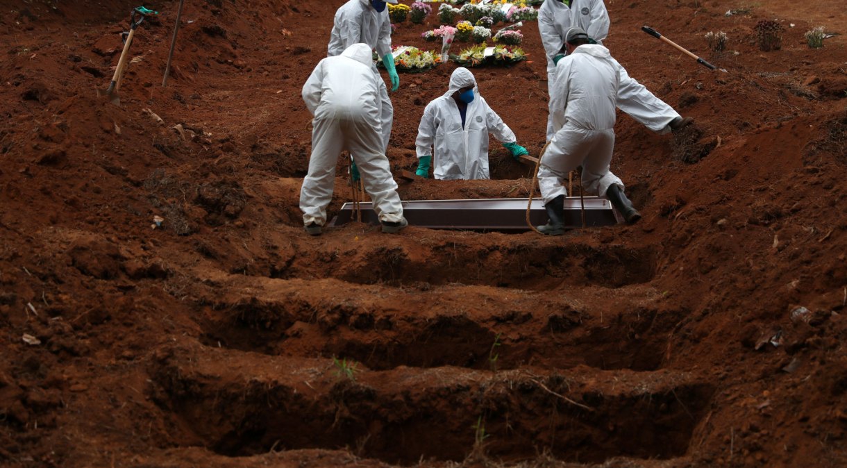 Coveiros em roupas de proteção enterram vítima da Covid-19 no cemitério São Luiz, em São Paulo