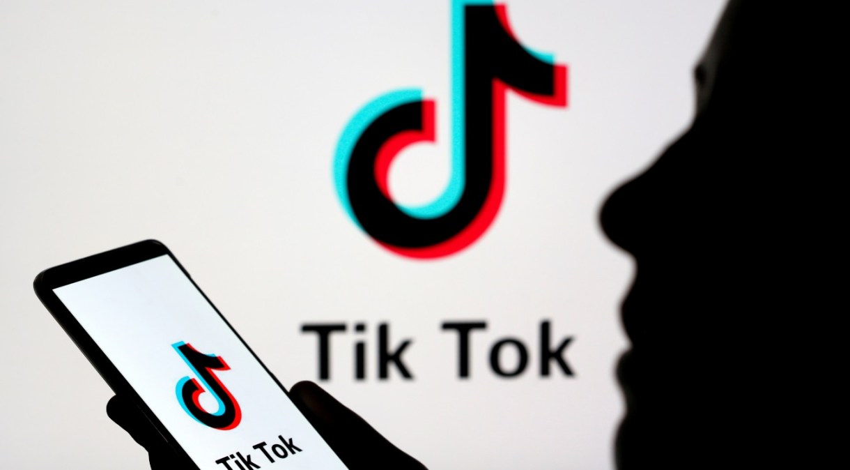 Jovem manipula smartphone com logotipo da TikTok