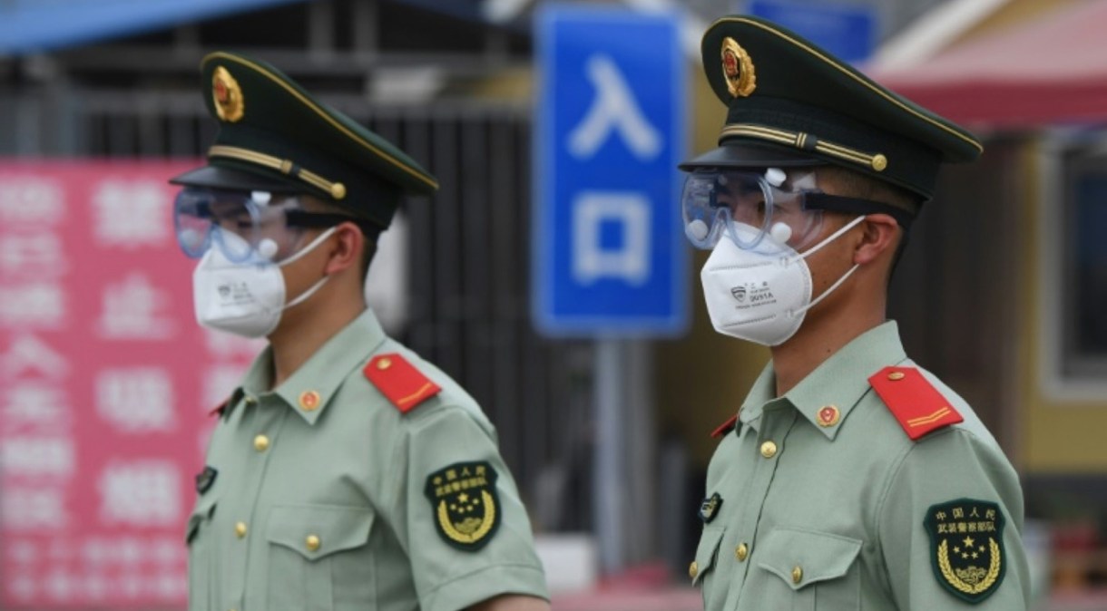 Policiais paramilitares usam máscaras e óculos de proteção enquanto ficam de guarda em uma entrada do mercado fechado de Xinfadi, em Pequim, em 13 de junho.