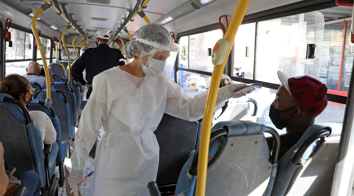 Profissional de saúde afere temperatura de passageiro em ônibus em Belo Horizonte