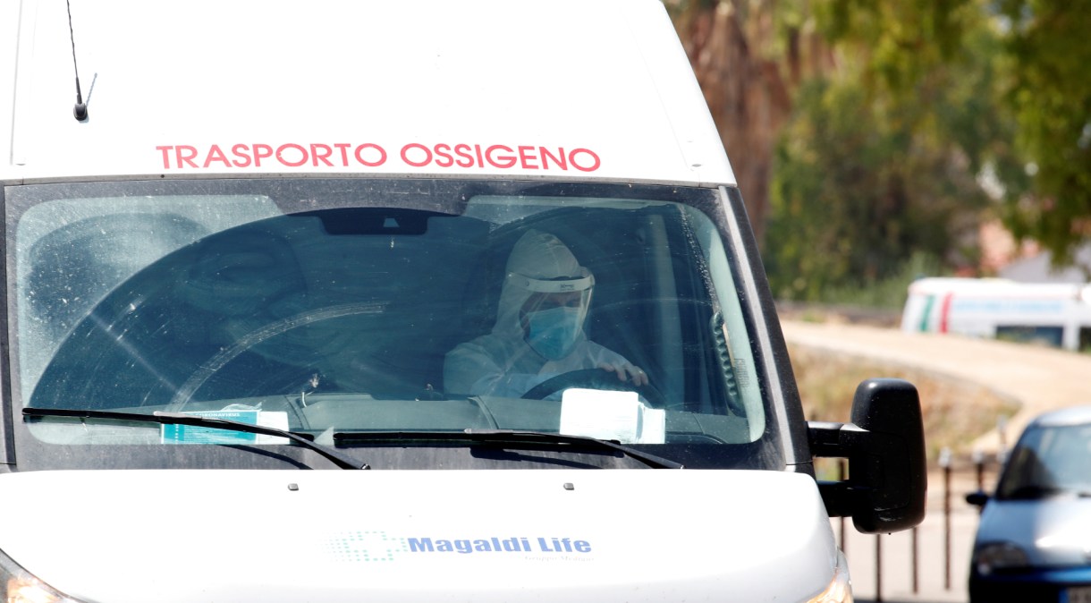 Profissional de saúde com trajes de proteção dentro de van em Mondragone, na Itália