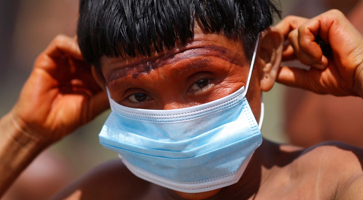 Indígena do povo ianomâmi segura máscara de proteção em Alto Alegre, Roraima