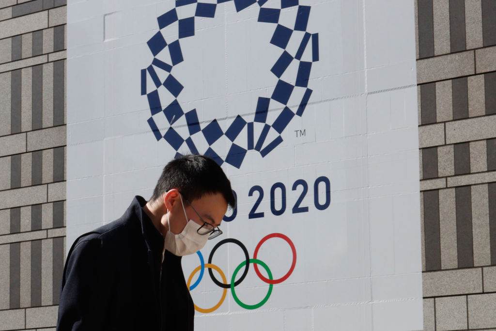 Homem de máscara passa em frente ao símbolo da Olimpíada de Tóquio