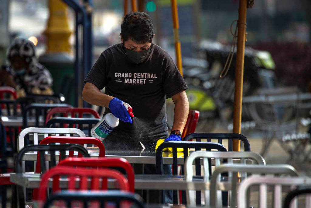 Funcionário higieniza mesas para reabertura de restaurantes