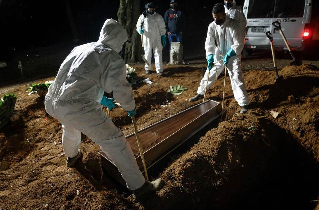 Funcionários do cemitério de Vila Formosa, em SP, carregam caixão de vítima da Covid-19; devido ao elevado número de óbitos, os funcionários também trabalham no período noturno