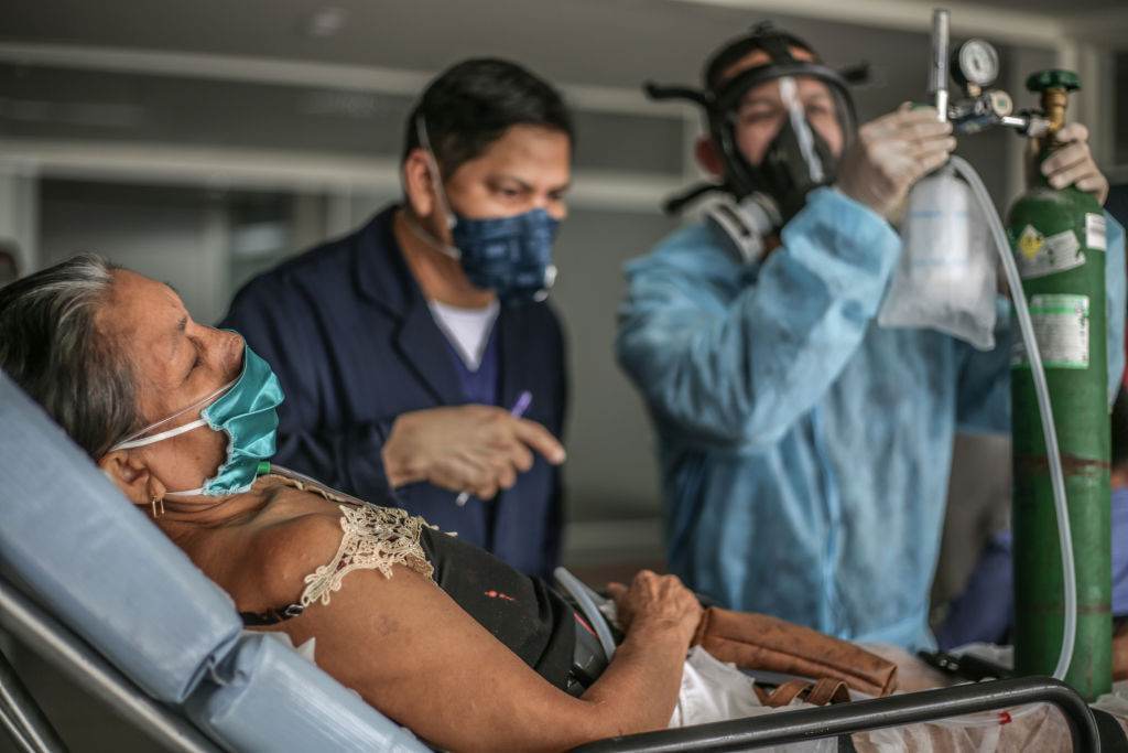 Um médico observa enquanto uma enfermeira verifica o fluxo de oxigênio de uma mu
