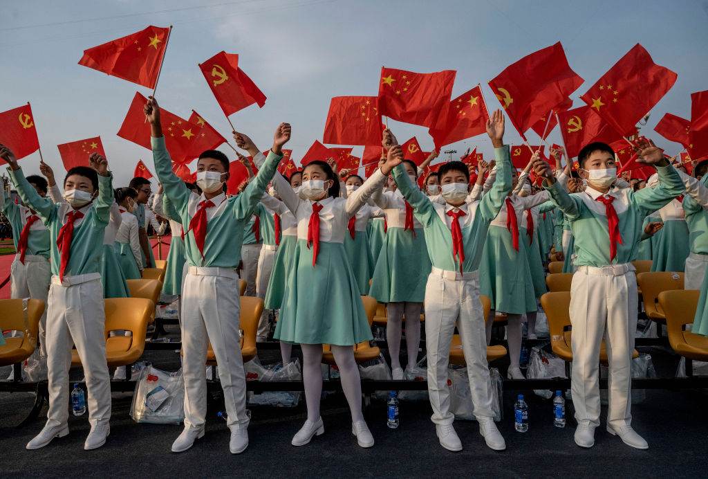Estudantes chineses cantam em coral com bandeiras nacionais 