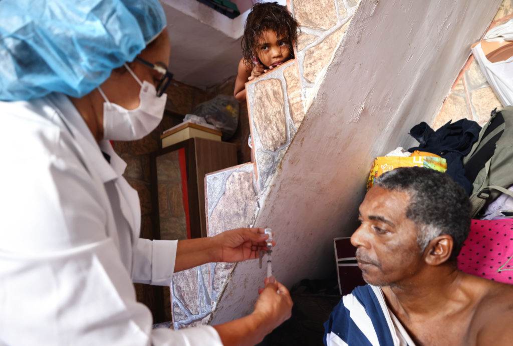 Enfermeira do SUS aplica vacina em homem em sua casa na Rocinha