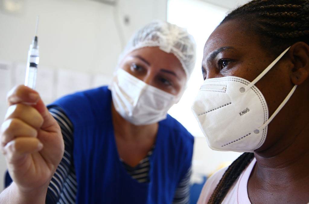 Enfermeira mostra vacina para mulher no Rio de Janeiro