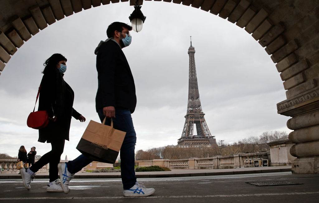 Pessoas andam em Paris com máscaras