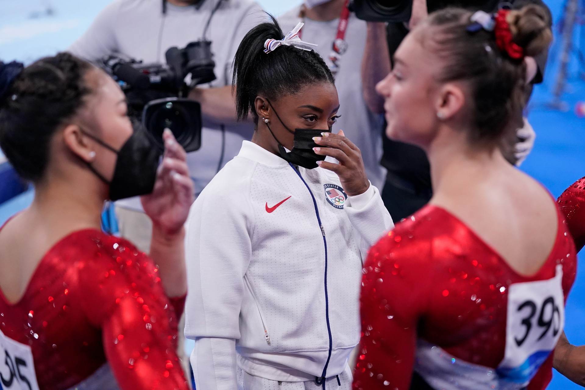 Simone Biles (de máscara) ao lado das outras ginastas dos EUA nas Olimpíadas