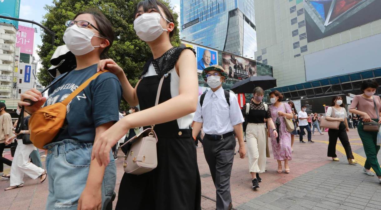 Com máscaras de proteção, japoneses caminham por rua de Tóquio