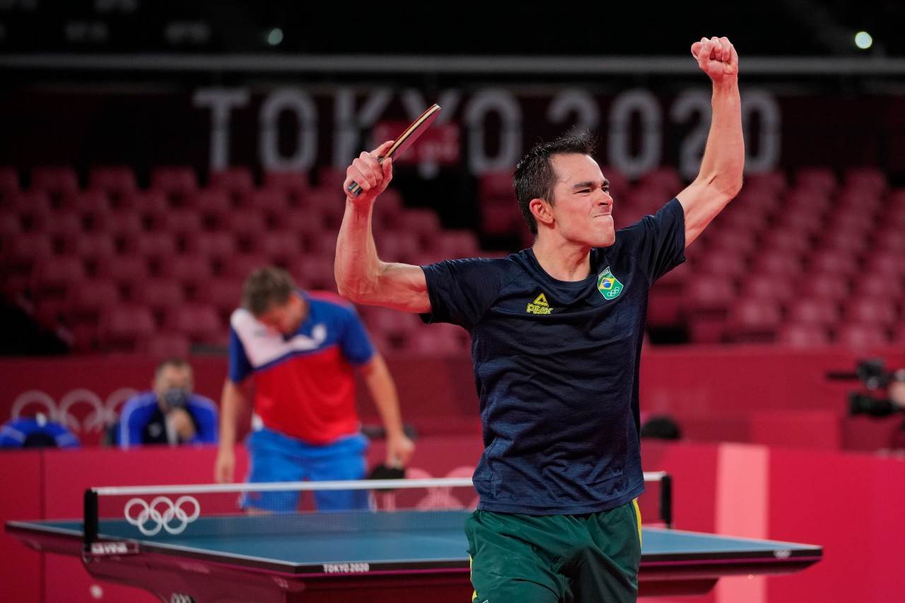 Hugo Calderano vibra com os braços erguidos após vitória no tênis de mesa