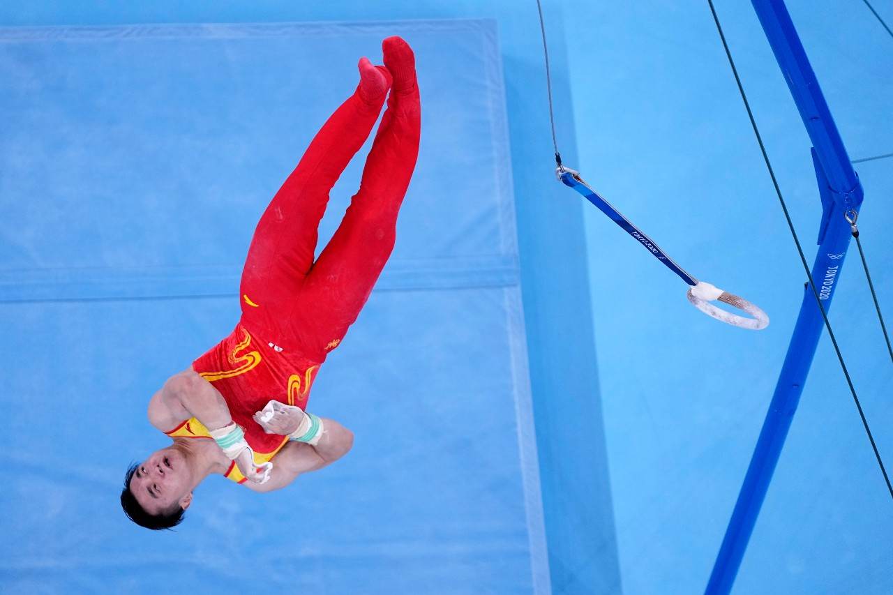 Ginasta chinês Liu Yang de ponta cabeça dando salto mortal na saída das argolas