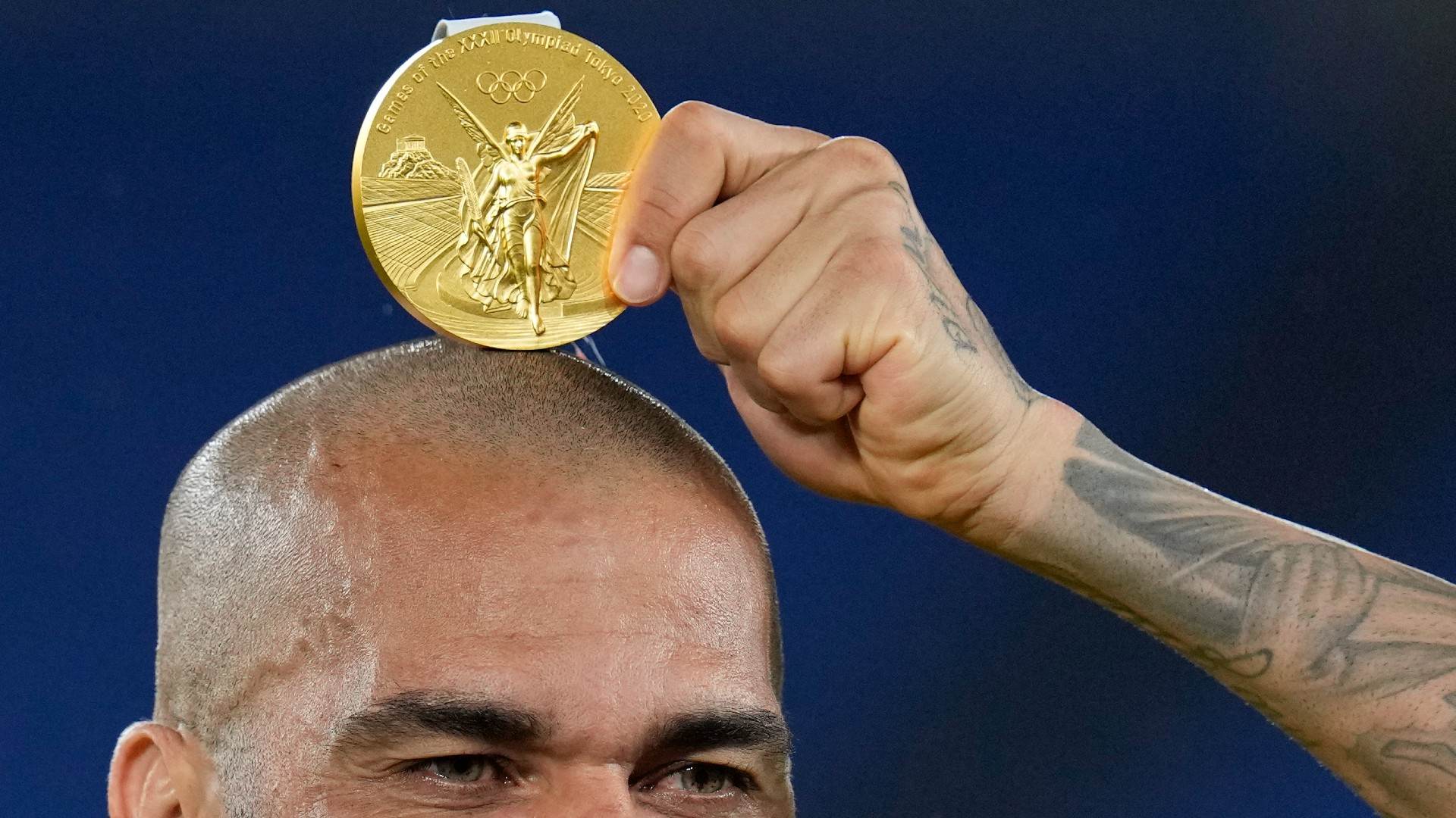 Dani Alves tira foto com medalha de ouro sobre a cabeça após conquista olímpica