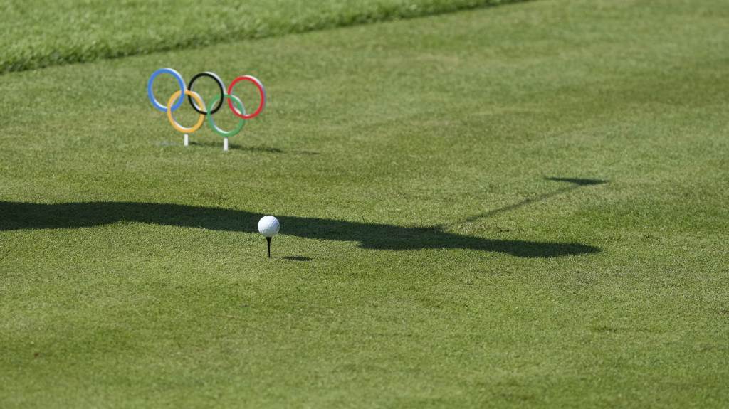 Silhueta de Xander Schauffele (EUA) com sua bola e os anéis olímpicos no torneio de golfe em Tóquio