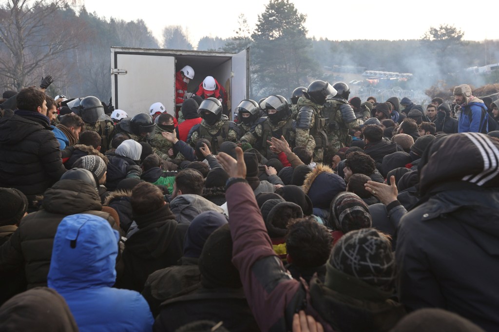 Migrantes tentam se aproximar de caminhão durante distribuição de ajuda humanitária na fronteira entre Belarus e Polônia