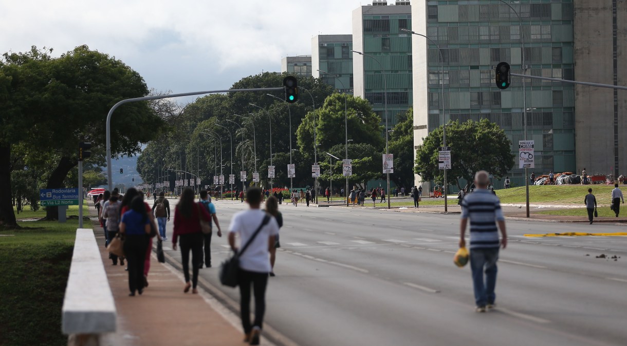 Pessoas caminham pela Esplanada dos Ministérios em Brasília