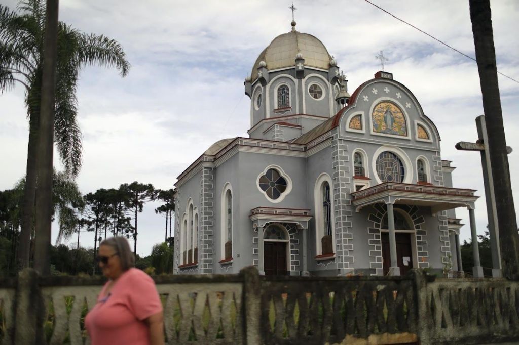 Mulher caminha em frente a uma igreja em Prudentópolis