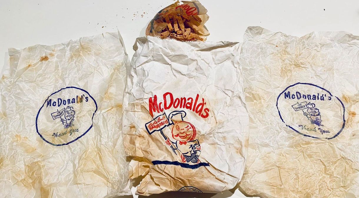Casal encontra duas embalagens de hambúrguer e uma porção de batatas fritas em uma sacola do McDonald's atrás da parede do banheiro