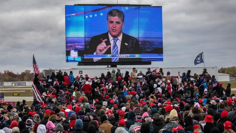 Apoiadores do presidente Donald Trump assistem a um vídeo com o apresentador da Fox News, Sean Hannity, antes da chegada de Trump a um comício de campanha em Michigan em 30 de outubro de 2020