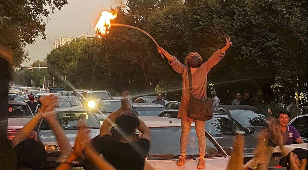 Uma mulher iraniana em cima do capô de carro incendeia seu lenço na cabeça no centro de Teerã durante protestos por Mahsa Amini, 22, que morreu depois que ela foi presa pela polícia de moralidade do Irã por "hijab impróprio"