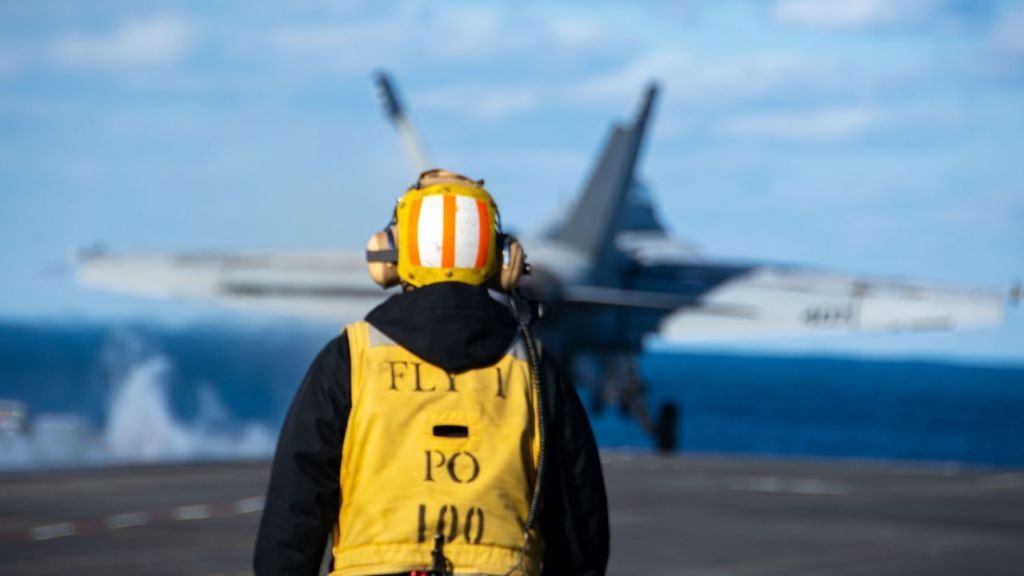 Trabalhador observa o lançamento de um F/A-18E Super Hornet a bordo de um porta-aviões dos EUA no Mar do Japão em 5 de outubro.