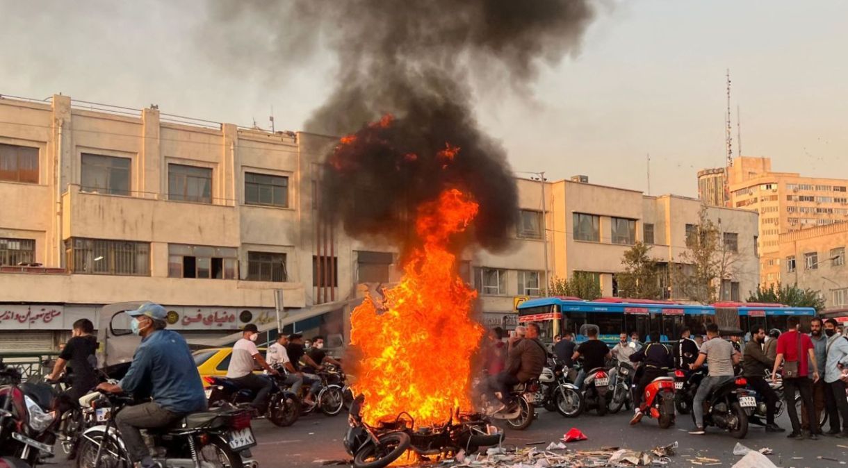 Pessoas se reúnem ao lado de uma motocicleta em chamas na capital iraniana, Teerã, em 8 de outubro de 2022.