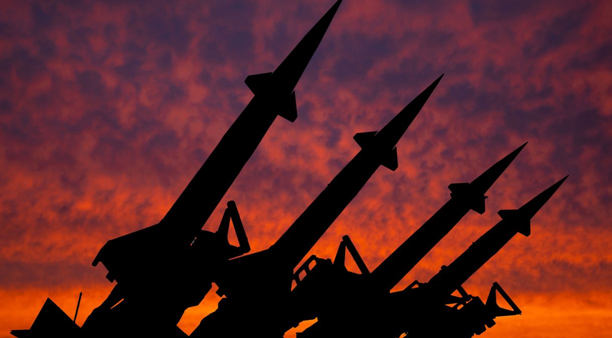 Quatro foguetes do sistema de mísseis antiaéreos são direcionados para cima no contexto do pôr do sol.