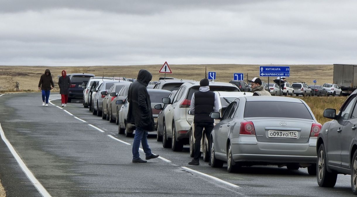 Pessoas caminham ao lado de seus carros enquanto fazem fila para cruzar a fronteira com o Cazaquistão no posto fronteiriço de Mariinsky, Rússia, em 27 de setembro.