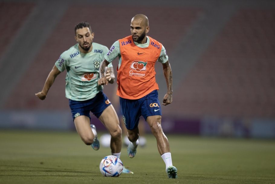 Daniel Alves corre sob os olhares de Alex Telles em treino da Seleção Brasileira no Estádio Grand Hamad, em Doha, Catar