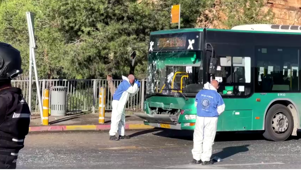 Um especialista em desarmamento de bombas e a polícia israelense trabalham ao lado de um ônibus danificado após uma explosão em Jerusalém em 23 de novembro