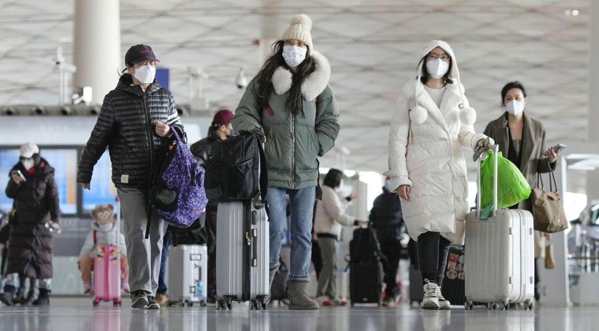 Passageiros usando máscaras puxam bagagem em um saguão de embarque no Aeroporto Internacional Capital de Pequim em 27 de dezembro de 2022, depois que o governo central abandonou recentemente sua política de "covid zero".