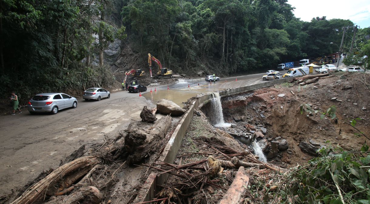 Trabalhadores usam máquinas para bater pedras e reabrir a galeria pluvial que foi afetada na Rodovia Rio-Santos