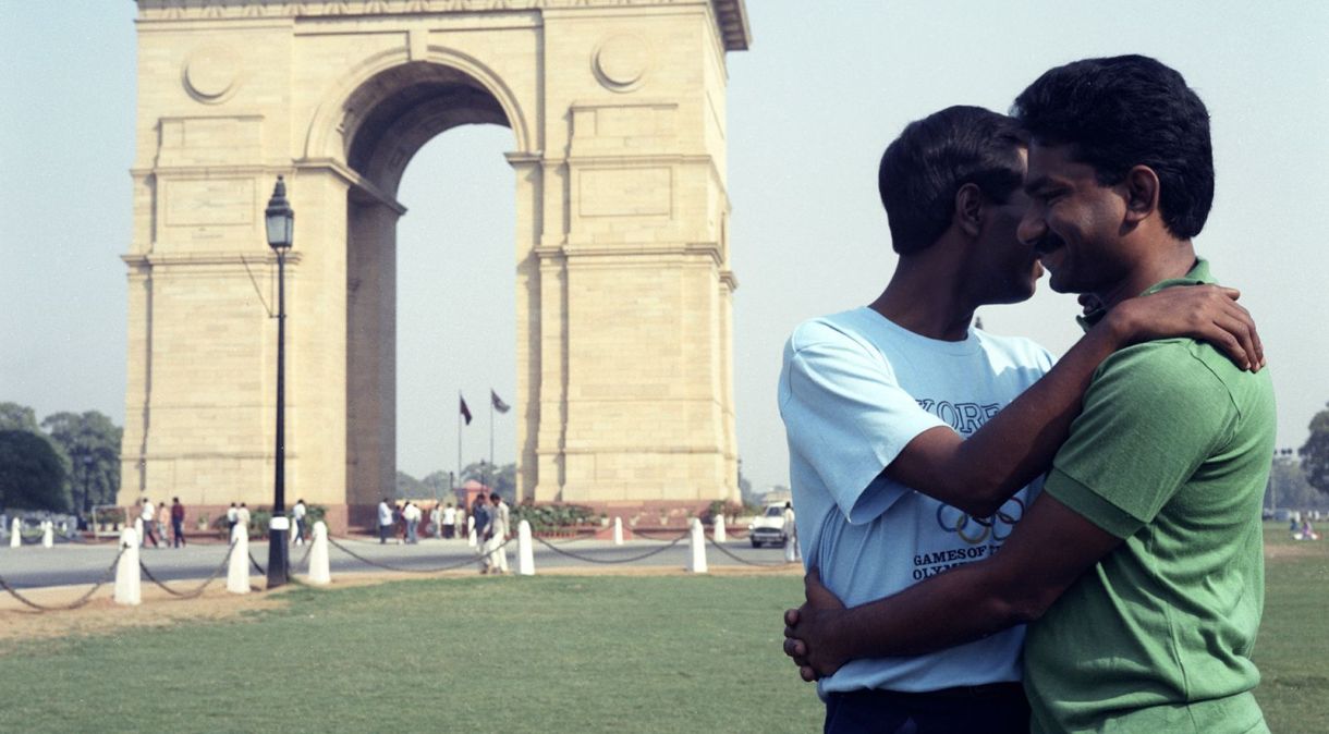 Fotografados por Sunil Gupta, dois homens se abraçam perto do Portão da Índia