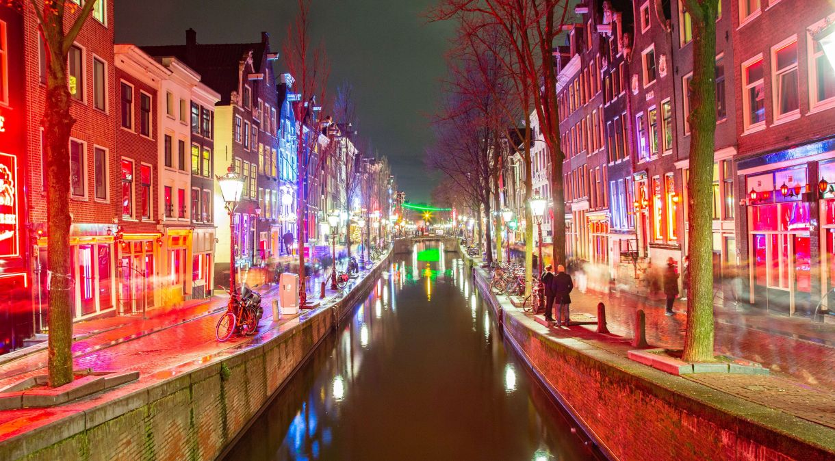 Noite no Red Light District de Amsterdã perto do canal e reflexo de casas iluminadas à noite na parte antiga da cidade