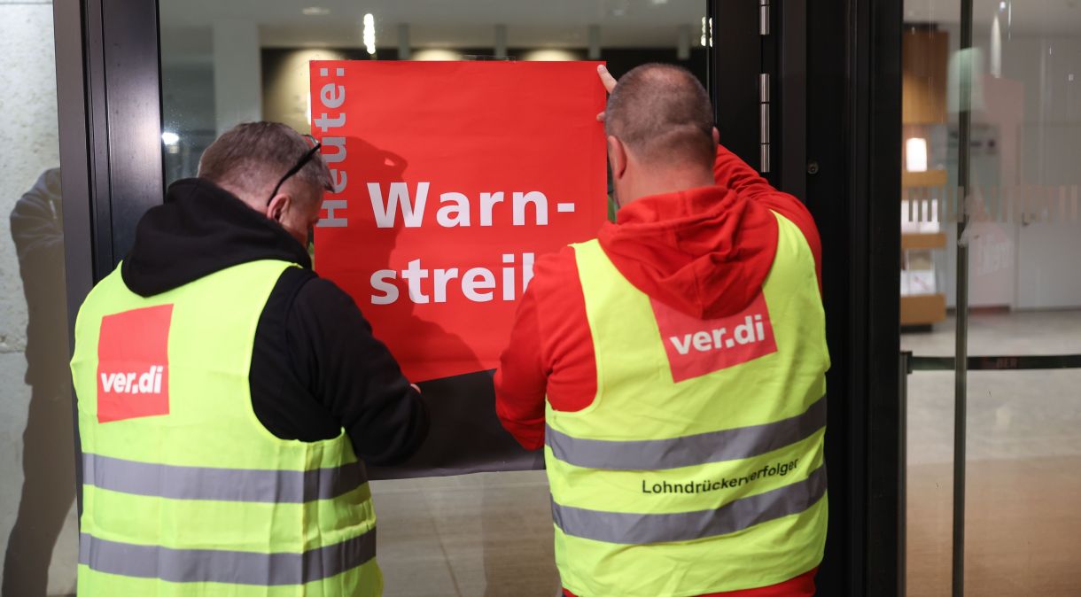 Grevistas fixam um cartaz com a inscrição "aviso de greve" no aeroporto de Berlim.