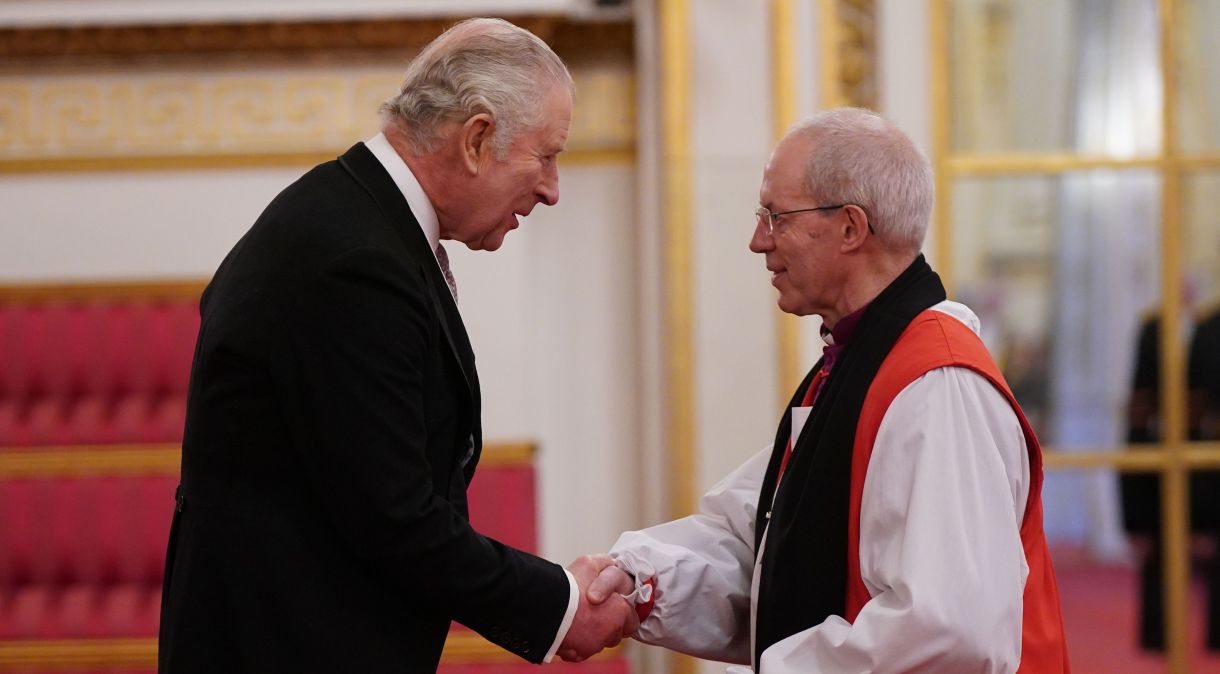 Rei Charles III cumprimenta o arcebispo da Cantuária Justin Welby em cerimônia no Palácio de Buckingham, em março de 2023.