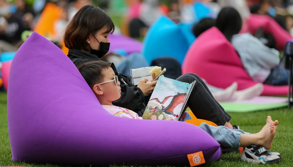 Uma criança lê um livro no Seoul Plaza em Seul, Coreia do Sul, em 23 de abril de 2023