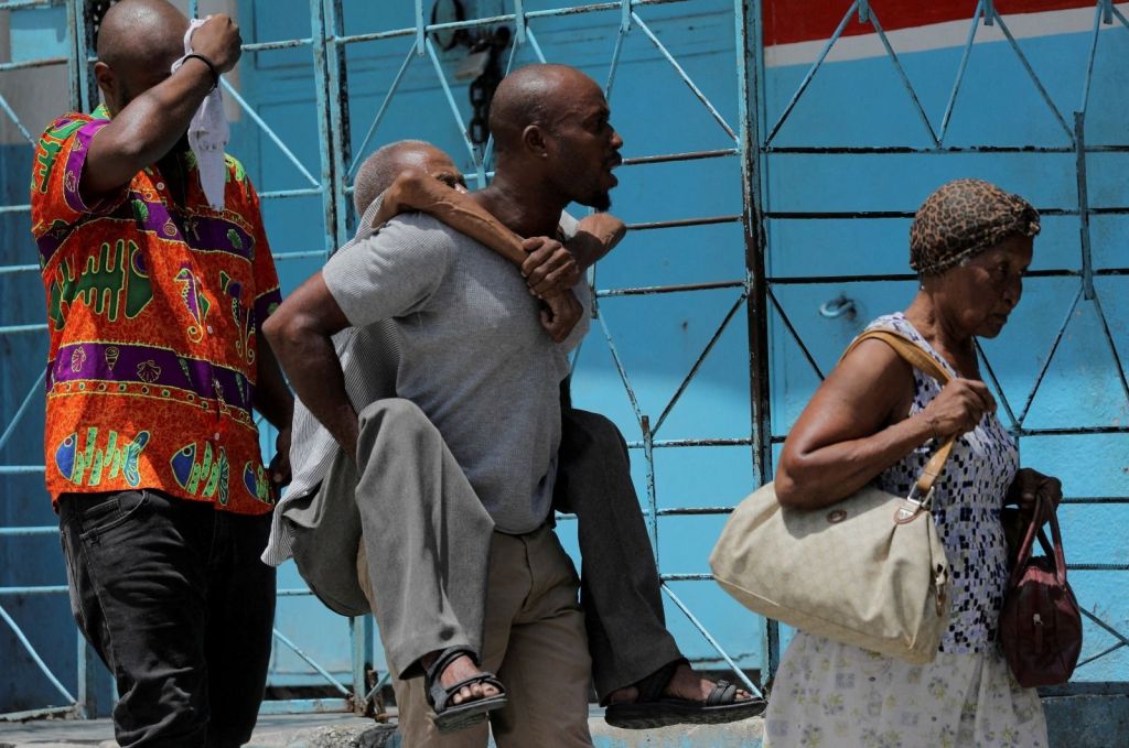 Homens carregam idosos enquanto fogem do bairro Carrefour Feullies em Porto Príncipe, no Haiti