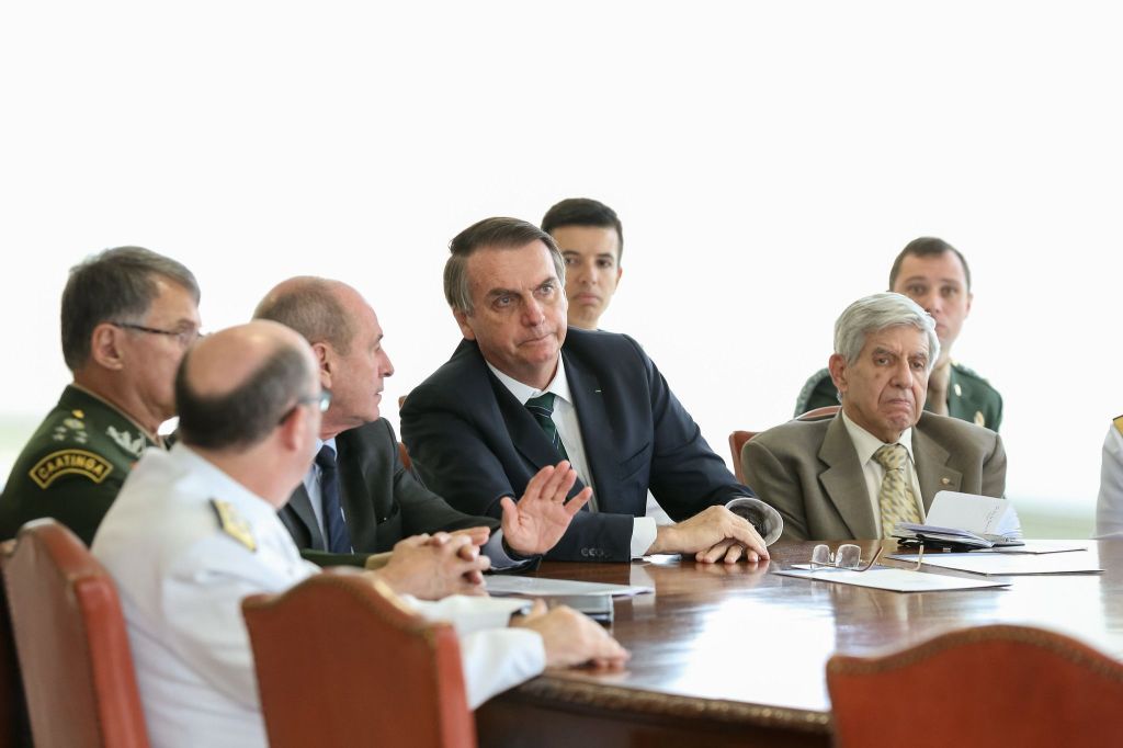 Foto mostra Ex-presidente Jair Bolsonaro (PL) em reunião com ex-ministro do GSI general Augusto Heleno e comandantes das Forças Armadas em fevereiro de 2019. Ex-ajudante de ordens Mauro Cid aparece sentado ao fundo.Mauro Cid acompanhando reunião de Heleno, Bolsonaro e Forças Armadas em fevereiro de 2019.