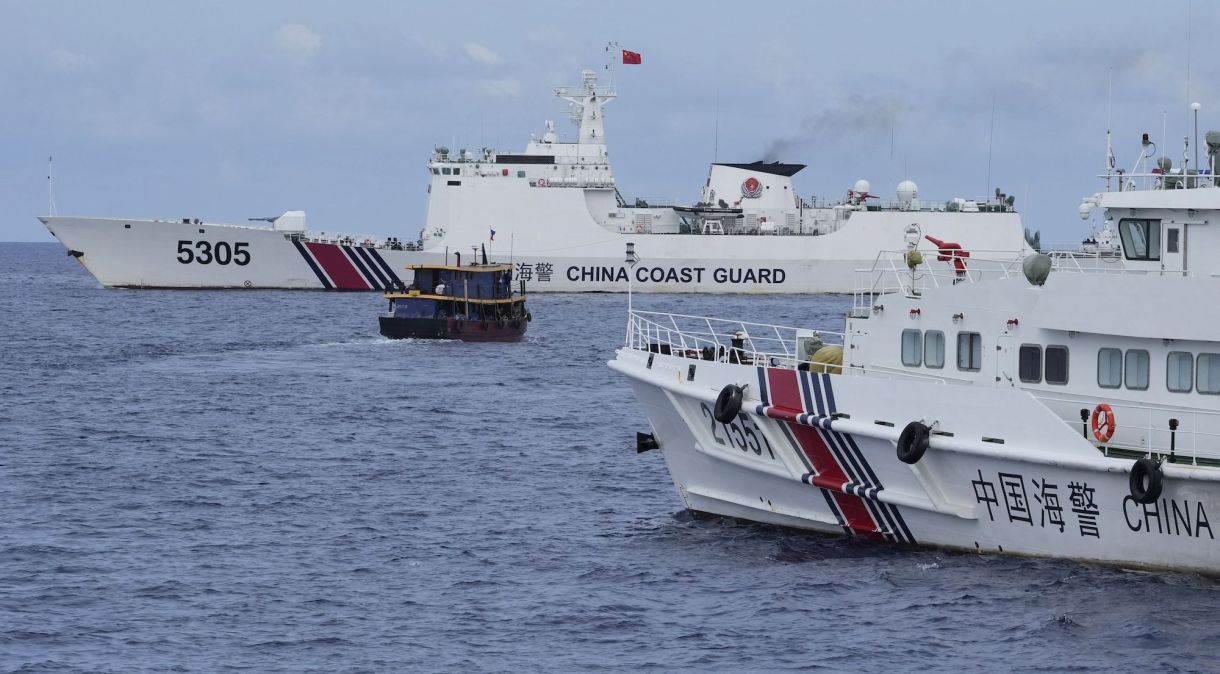 Um barco de abastecimento filipino, no centro, manobra em torno dos navios da guarda costeira chinesa enquanto eles tentavam bloquear seu caminho
