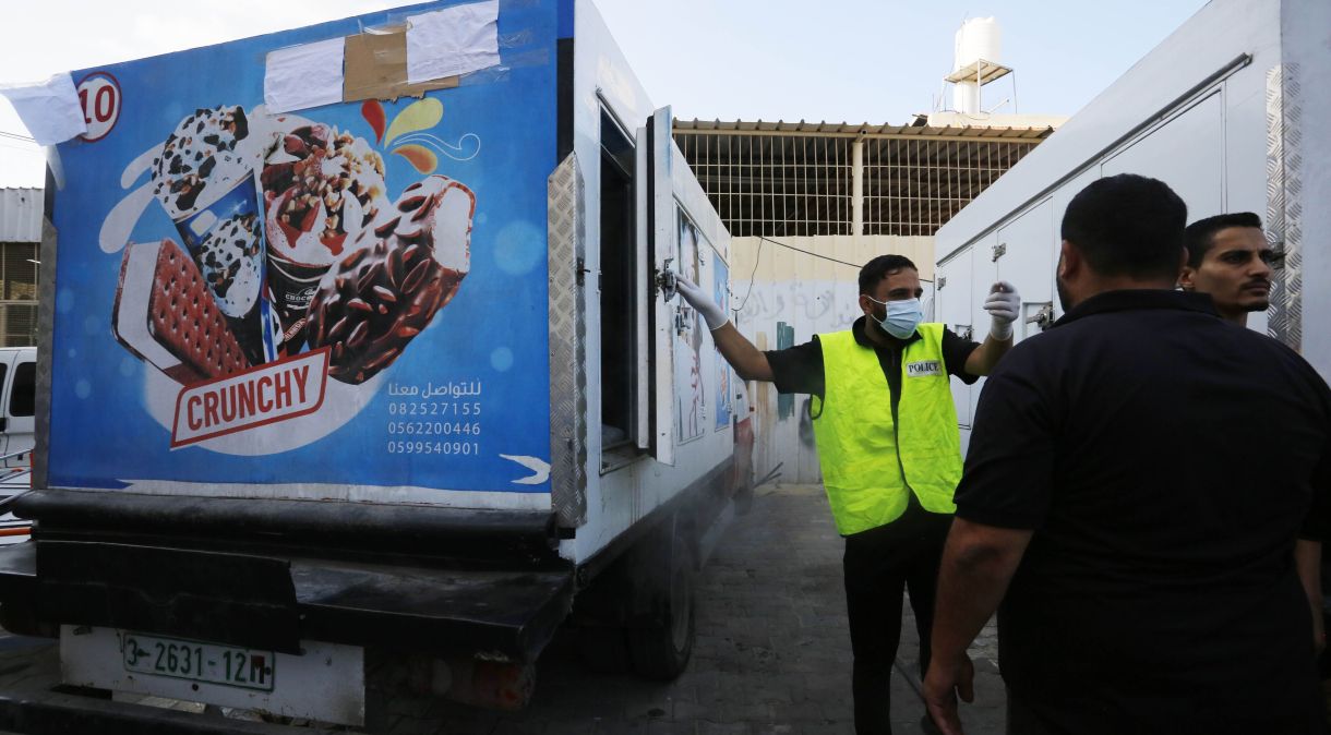 Um policial coloca cadáveres em geladeiras de sorvete devido à falta de necrotérios do Hospital dos Mártires de Al-Aqsa