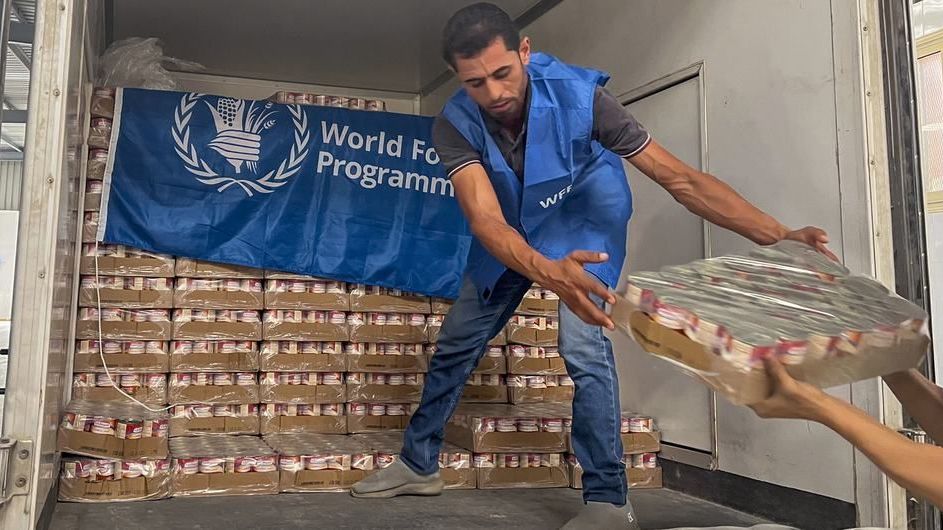 Trabalhador descarrega alimentos prontos para consumo de um caminhão perto de Alexandria, no Egito, em preparação para entrega em Gaza