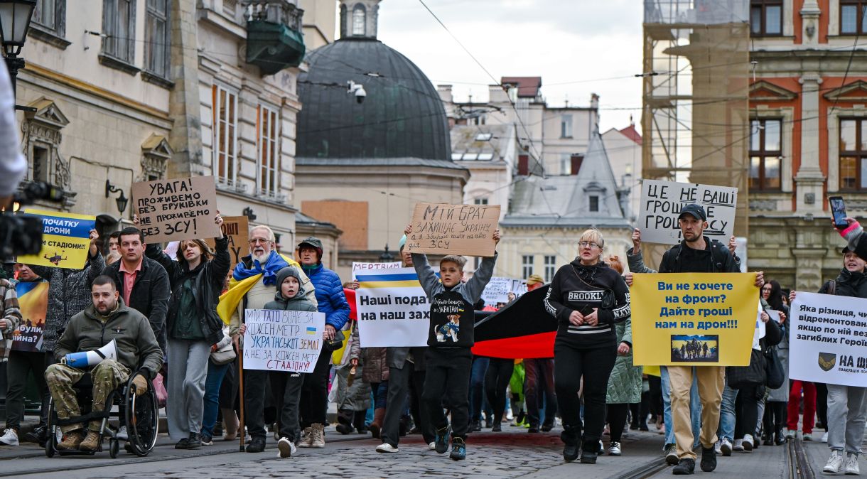 Manifestantes caminham por uma rua enquanto pedem para cortar gastos orçamentários não críticos e dar dinheiro aos militares ucranianos